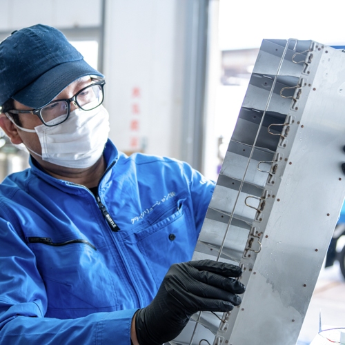 従業員の男性が液体窒素容器のラックを抱えて見ている写真